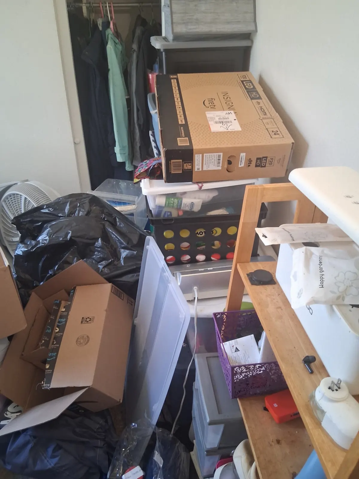 Bedroom stacked with boxes, bins and shelving before an apartment cleanout