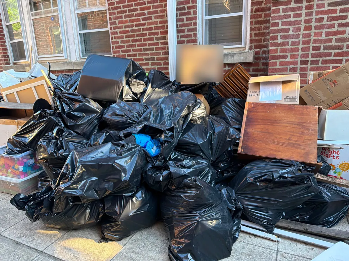 Bagged junk, boxes and furniture from a house cleanout outside a Brooklyn brick building