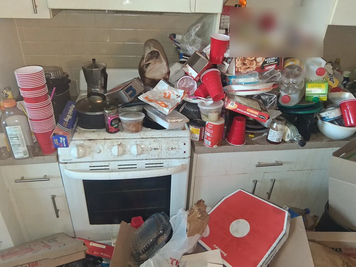 Kitchen counters and stove buried in clutter before a hoarding cleanout