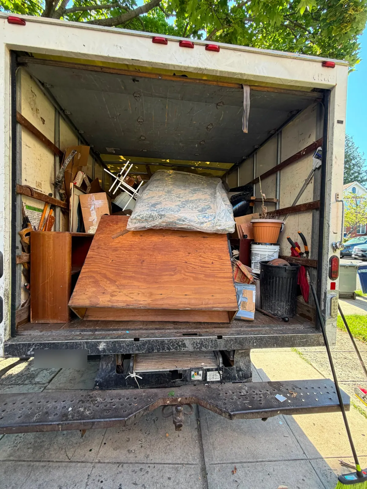 Junk All Mighty box truck with a full load of furniture and household junk on a Brooklyn street