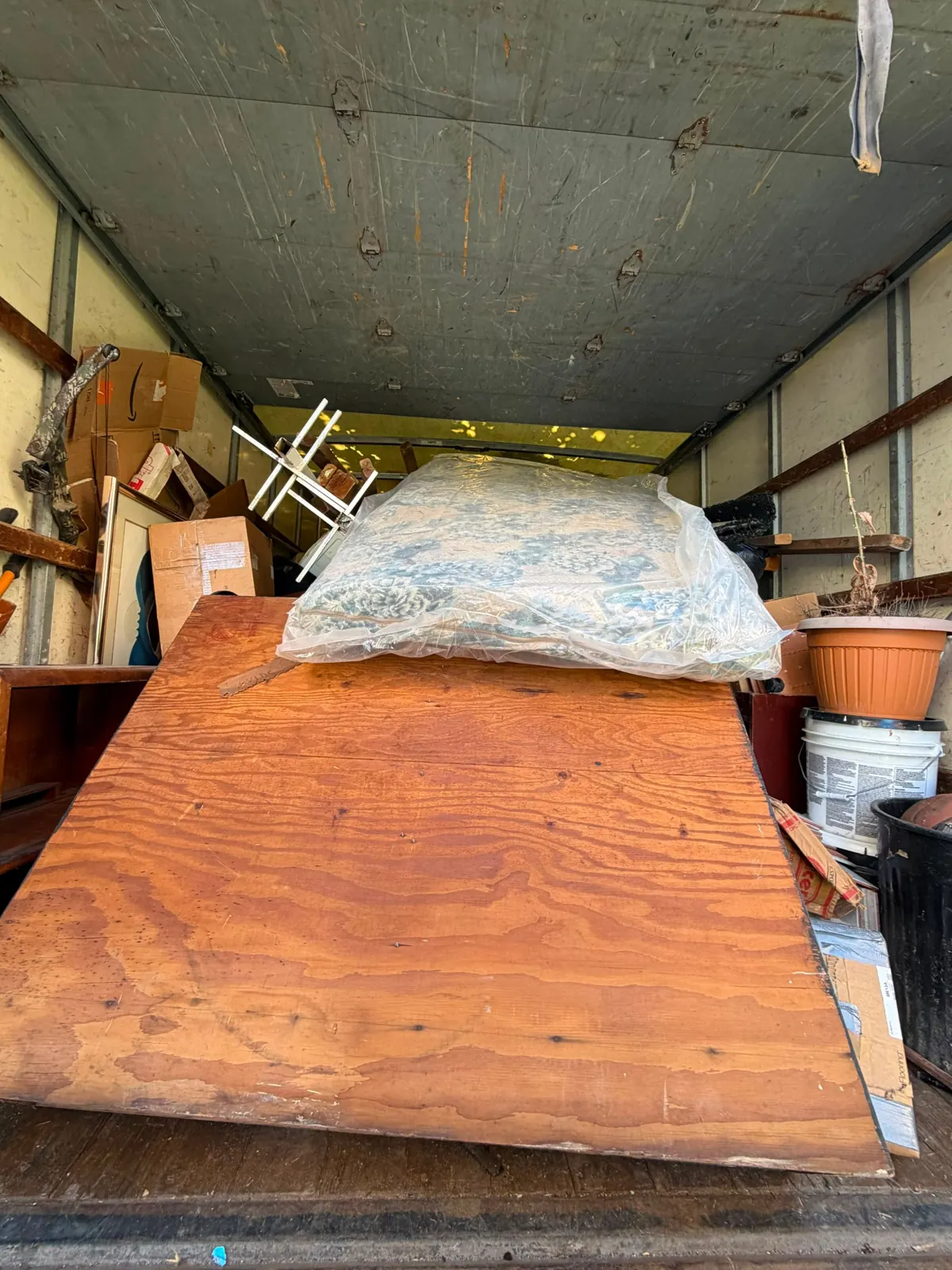 Furniture, boxes and a plastic-wrapped mattress loaded in a junk removal truck